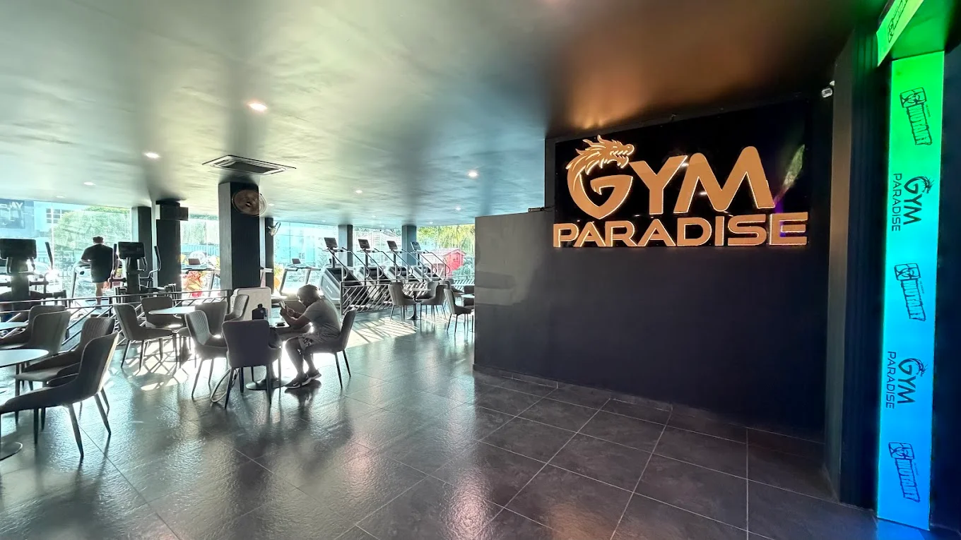 Reception and lounge with GYM PARADISE logo wall